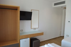 A hotel room with a wooden wardrobe, a small refrigerator, a flat-screen TV mounted on the wall, and a bed with white bedding. - Hotel Paja (Ksamil)
