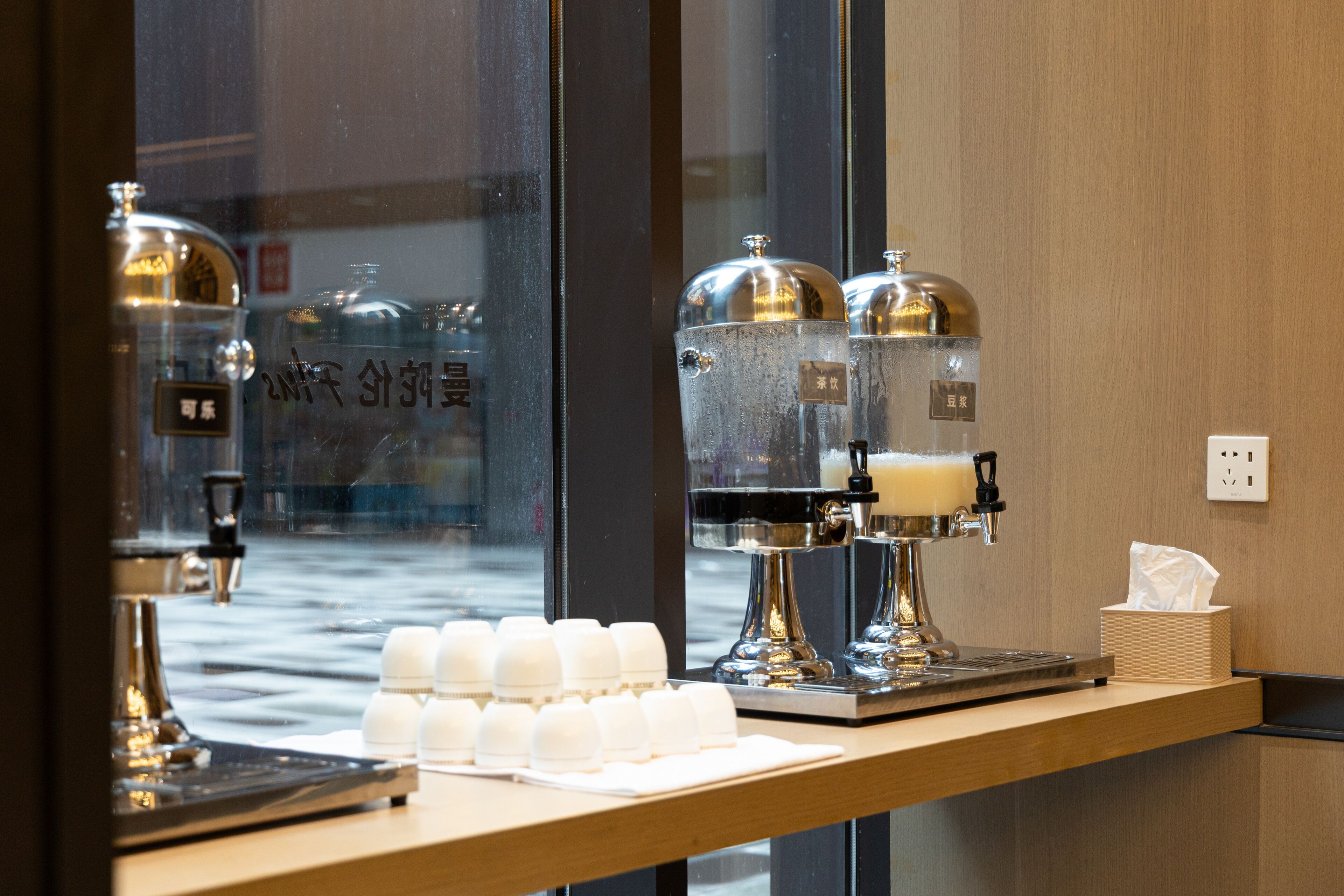 A coffee station with a coffee machine, milk frothing machine, and cups on a wooden counter.