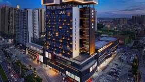 Un hotel moderno con varios pisos, una terraza en la azotea y un estacionamiento.