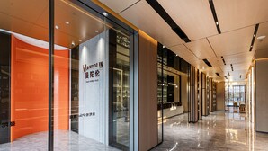 Un pasillo moderno de hotel con puertas de vidrio, un cartel que dice "MINDOLN Smart Hotels Plus" y un suelo de mármol reflectante.