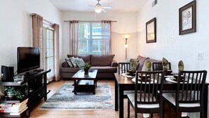A living room with a sofa, coffee table, TV, and dining area with chairs and a table. - EPIC VALUE-Disney Retreat! Magical Kid Friendly! (Kissimmee)