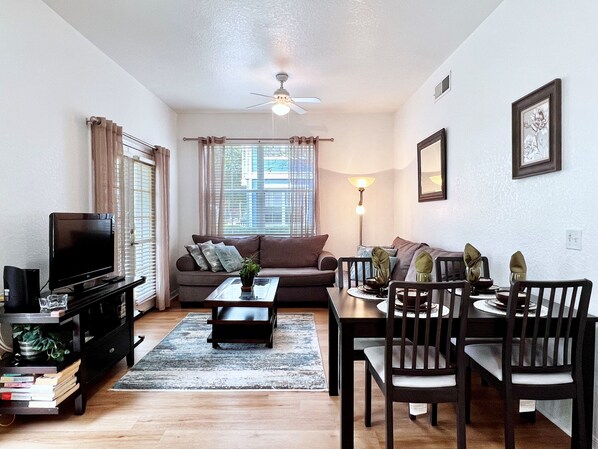 A living room with a sofa, coffee table, TV, and dining area with chairs and a table. - EPIC VALUE-Disney Retreat! Magical Kid Friendly! (Kissimmee)