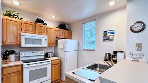 A compact kitchen with wooden cabinets, a microwave, a stove, a refrigerator, and a sink. - EPIC VALUE-Disney Retreat! Magical Kid Friendly! (Kissimmee)