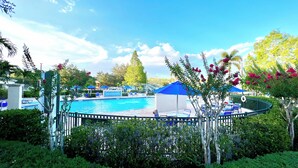 A pool area with blue umbrellas, lounge chairs, and a fenced deck. - EPIC VALUE-Disney Retreat! Magical Kid Friendly! (Kissimmee)