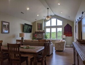 Relax in a spacious living area with a high ceiling, fireplace, and large window offering a view of the outdoors.