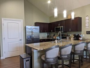 Enjoy cooking in this well-equipped kitchen with a central island, bar stools, and stainless steel appliances.