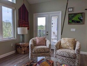 Relax in this inviting living room with two comfortable armchairs, a coffee table, and a lamp on a stool.