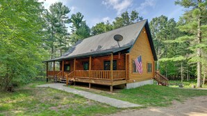 Una baita di tronchi con un portico, un’antenna parabolica e una bandiera americana.
