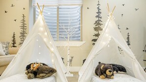 Une pièce chaleureuse avec deux petites tentes blanches, chacune contenant un animal en peluche.
