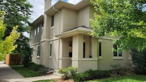 Une maison à deux étages avec un porche à l’avant, un hall d’entrée couvert et un petit jardin devant, agrémenté d’un arbre et de quelques arbustes.