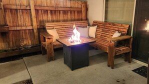 Un ensemble de banc et de table en bois, avec un foyer au centre.