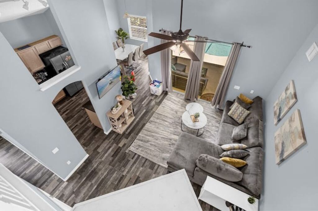 Una sala moderna con un sofá gris, una mesa de centro y un ventilador de techo.