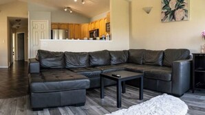 A modern living room with a sectional sofa, a coffee table, and a fireplace. - Beautiful home in quiet neighbourhood, sleeps 10! (Grande Prairie)