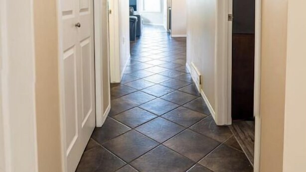 A hallway with dark tiled flooring, white walls, and a ceiling light fixture. - Beautiful home in quiet neighbourhood, sleeps 10! (Grande Prairie)
