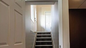 A narrow staircase with dark tiles leading to a door at the top. - Beautiful home in quiet neighbourhood, sleeps 10! (Grande Prairie)