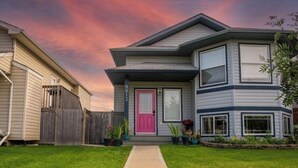 A two-story house with a visible address number, a front porch, and a well-maintained lawn. - Beautiful home in quiet neighbourhood, sleeps 10! (Grande Prairie)