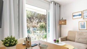 A modern living room with a sofa, a coffee table, and a dining table with a plant and a coffee maker. - Sea apartment 1A with pool, 2 min. canyamel beach (Capdepera)