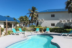 A pool area with lounge chairs and a building with a blue roof.
