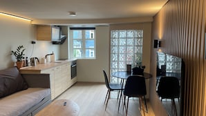 A modern kitchen with a dining area, wooden cabinets, a built-in oven, and a window with a view.