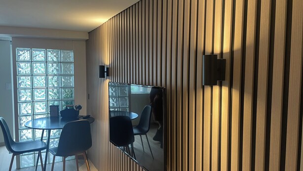 A modern dining area with a round table, black chairs, and a large mirror reflecting the room.