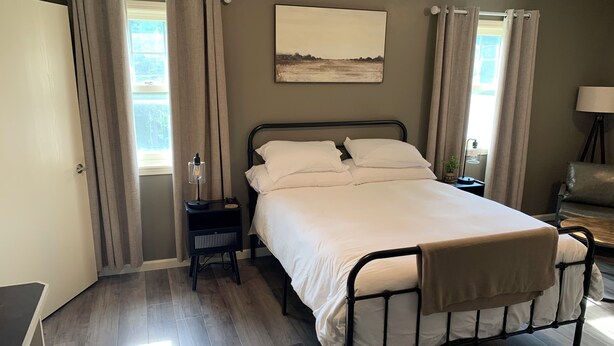 A bedroom with a bed, a nightstand, a lamp, and a window with curtains.