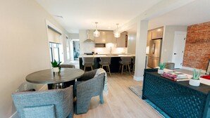 A modern kitchen with a central island, bar stools, pendant lighting, and a brick accent wall.