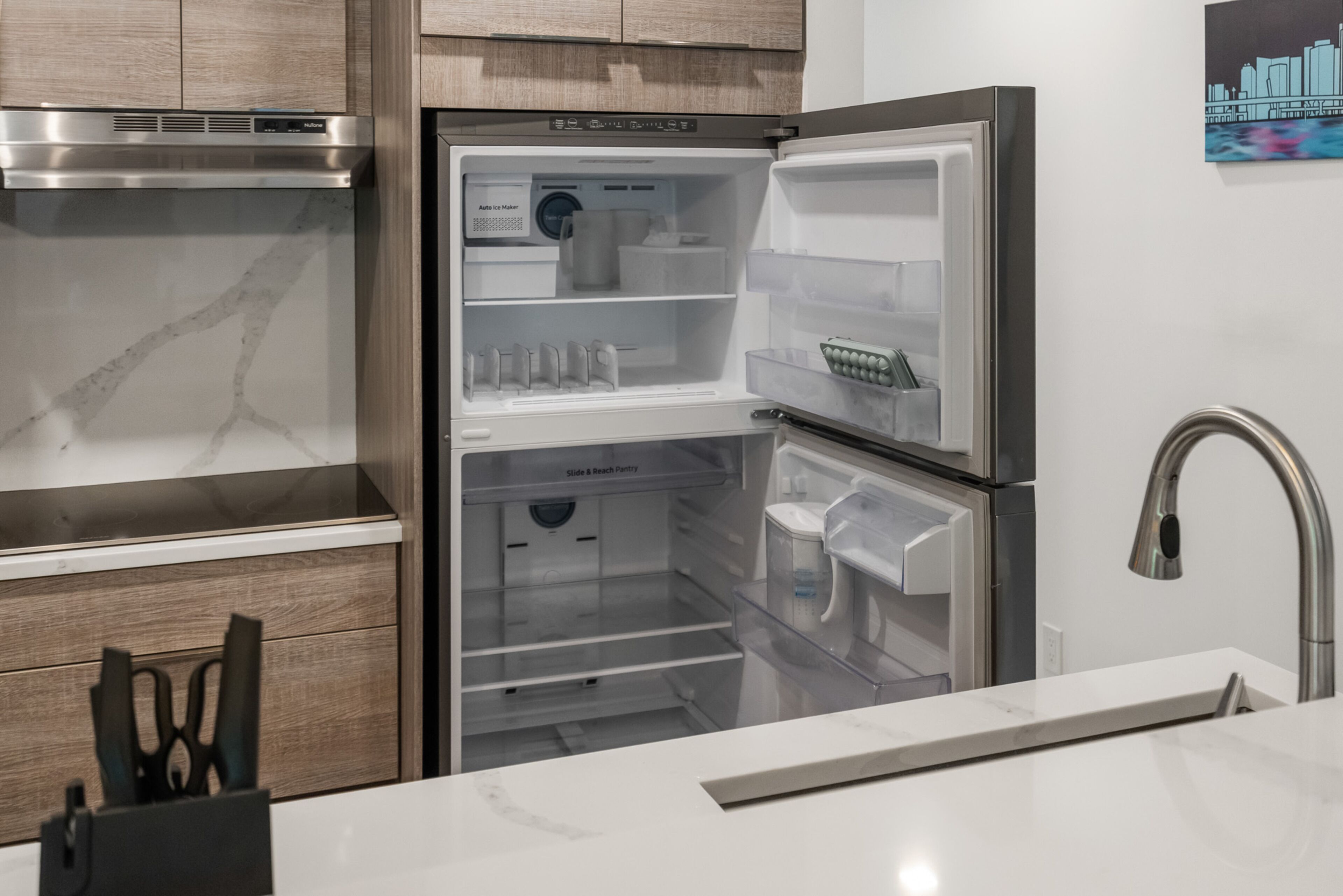 A modern kitchen with a built-in stainless steel refrigerator, a microwave, and a sink.