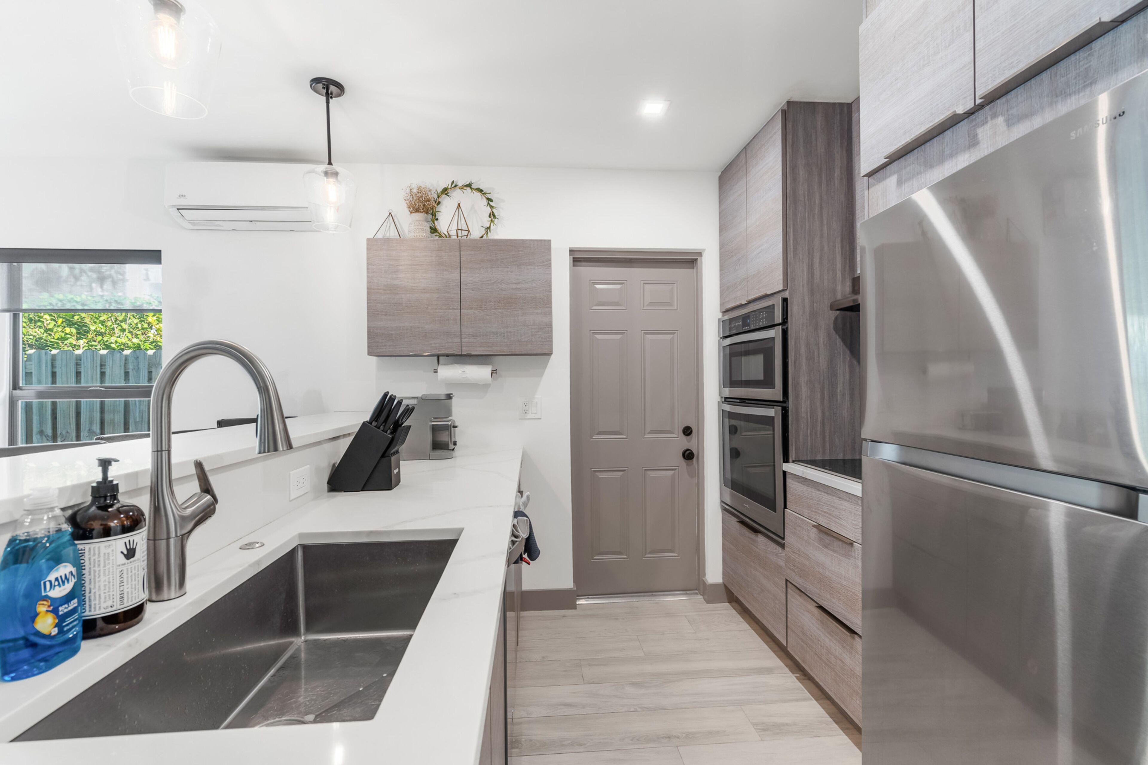 A modern kitchen with stainless steel appliances, a double sink, and wooden cabinetry.