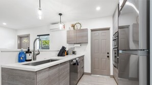 Cozinha moderna com ilha central, eletrodomésticos de aço inoxidável e janela com vista.