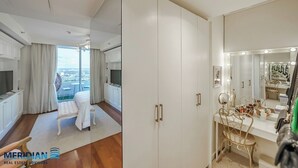 Quarto moderno com um guarda-roupa espaçoso, uma toucador com espelho e vista para a cidade.