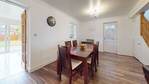 A dining area with a wooden table, chairs, a fruit bowl, and a clock on the wall. - Charming 5-bed House in Grays (Grays)
