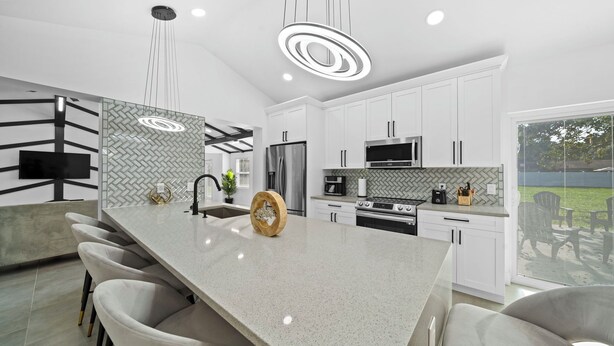 Una cocina moderna con una isla grande, electrodomésticos de acero inoxidable y un backsplash de baldosas en patrón de espiga.
