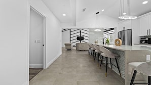 Una cocina moderna con barra, zona de comedor y sala de estar.