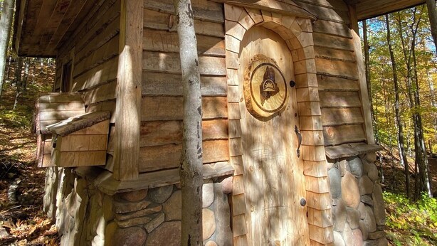 Una cabaña rústica con cimientos de piedra, paredes de madera y techo inclinado.