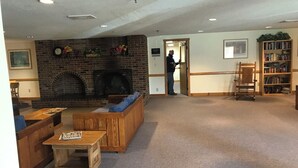 Una biblioteca acogedora con chimenea de ladrillo, muebles de madera y una estantería.