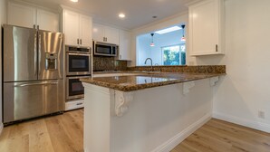 A modern kitchen with stainless steel appliances, granite countertops, and white cabinetry.