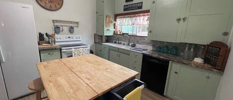 Una cocina compacta con una mesa de madera, un lavamanos y un reloj en la pared.