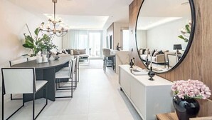 A modern dining area with a long table, chairs, and a chandelier. There is a large mirror on the wall and a vase with flowers on a side table. - Penthouse with sea views in San Pedro de Alcántara by Costarentals - Ref M34 (San Pedro Alcántara)