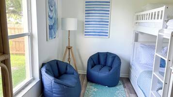 A room with a bunk bed, two bean bag chairs, a floor lamp, and a painting on the wall.