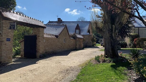Ein Steinhaus mit einem Schotterweg und einem Baum im Vordergrund.