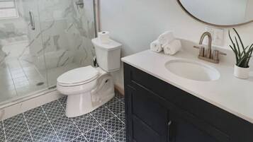 A bathroom with a toilet, sink, and shower area.