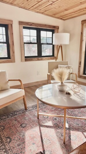 A room with a round table, two chairs, a floor lamp, and a window with a view.