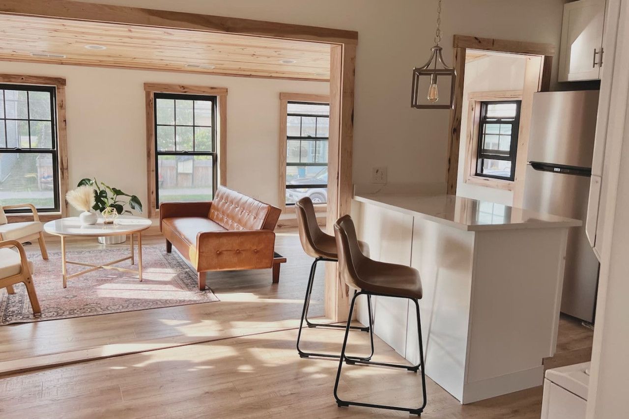 Una cocina moderna con barra, ventanas amplias y una zona de estar acogedora con sofá y sillones.