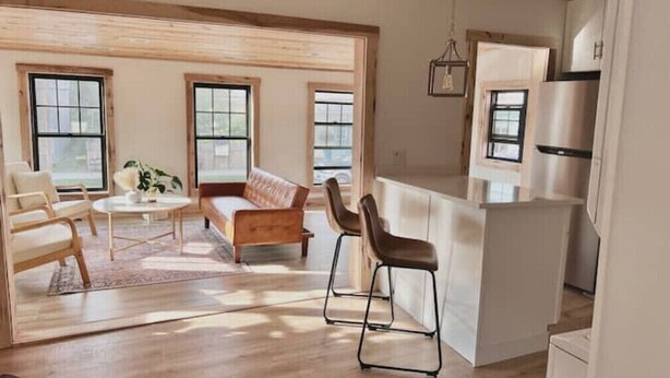 A modern kitchen with a central island, large windows, and a dining area with a sofa and chairs. - Uptown - Heart of Davis (Davis)