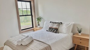 A bedroom with a bed, a window, a bedside table with a plant, and a nightstand. - Uptown - Heart of Davis (Davis)