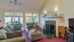 Un salón amplio con chimenea, televisor y un ventanal con vistas panorámicas.