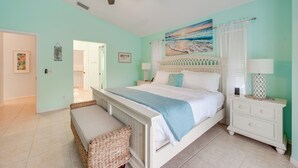 Une chambre à coucher avec un lit, des tables de chevet, un ventilateur de plafond et un tableau accroché au mur.