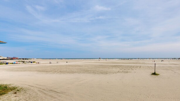 Une vaste plage de sable fin, sous un ciel dégagé.