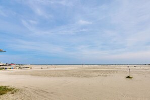 Une vaste plage de sable fin, sous un ciel dégagé.
