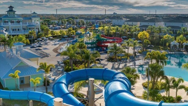 A water park with multiple slides and a swimming pool, surrounded by palm trees and buildings. - Magic Villa in Kissimmee with Private Pool (Kissimmee)